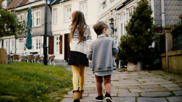 Two-little-kids-walk-together-near-old-buildings.-Children,-girl-and-boy-wander-around-beautiful-German-old-town.-4K