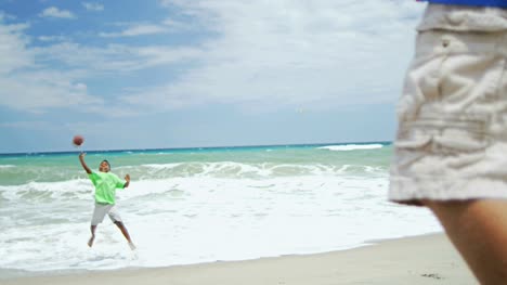 Americanos-africano-niños-jugando-a-la-pelota-en-vacaciones-en-la-playa