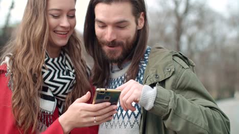 Young-happy-couple-using-smartphone-in-a-city.