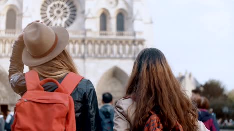 Vista-posterior-de-dos-mujer-de-viaje-con-mochila-a-pie-cerca-de-Notre-Dame,-Catedral-en-París,-Francia