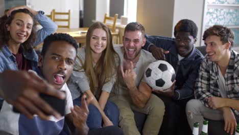 Compañía-de-los-aficionados-al-fútbol-tomando-Selfie-juntos-en-casa
