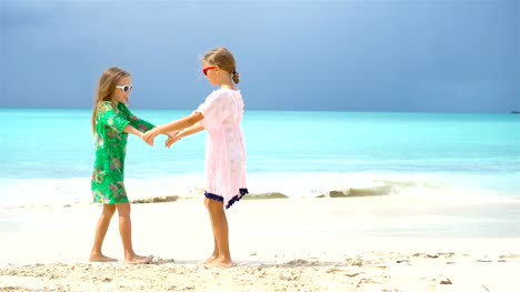 Entzückende-kleine-Mädchen-eine-Menge-Spaß-am-tropischen-Strand-spielen-zusammen