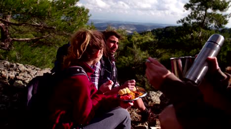 Amigos-de-excursionista-con-una-comida-en-la-cima-de-una-montaña