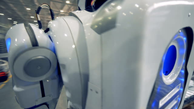 A-white-robot-carries-a-metal-item-at-a-factory,-close-up.