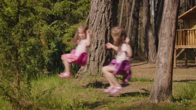 zwei-Mädchen-Schwingen-auf-der-Schaukel-im-Wald