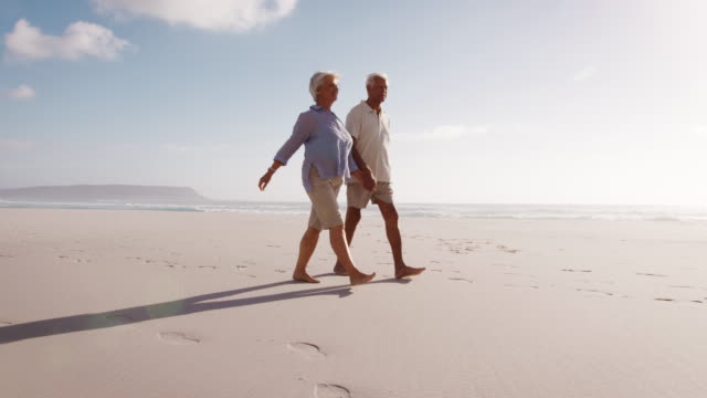 Vista-de-ángulo-bajo-de-la-romántica-pareja-Senior-en-vacaciones-de-verano-caminando-por-la-playa