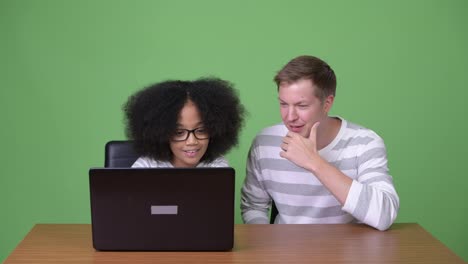 Young-African-girl-and-young-Scandinavian-man-using-laptop-together