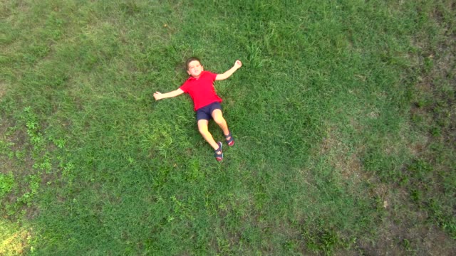 Little-boy-lying-down-in-the-middle-of-a-field.-Aerial-view