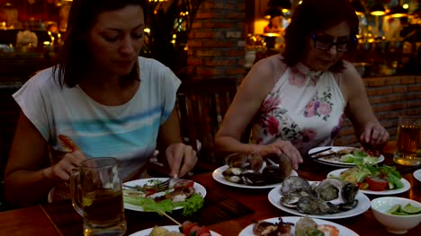 Frauen-im-Restaurant-Meeresfrüchte-essen-und-trinken-Bier