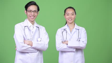 Médicos-de-la-joven-pareja-asiática-feliz-con-los-brazos-cruzados-juntos