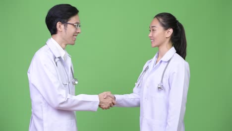 Young-Asian-couple-doctors-shaking-hands-together