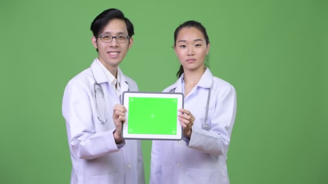 Junge-asiatische-paar-Ärzte-zeigt-digital-Tablette-zusammen
