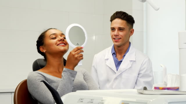 Beautiful-woman-checking-her-smile-in-the-mirror-at-the-dental-clinic