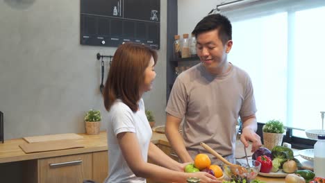 Asian-man-prepare-salad-food-in-the-kitchen.-Beautiful-happy-asian-couple-are-cooking-in-the-kitchen.-Young-asian-couple-have-romantic-time-while-staying-at-home.-Couple-lifestyle-at-home-concept.