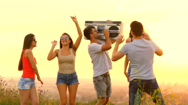 The-people-with-a-boom-box-dancing-on-the-sunrise-background.-slow-motion