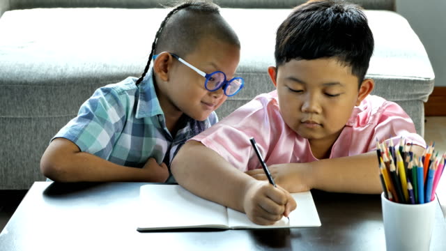 Boys-with-disability,-brain-disorders-And-Left-eye-is-not-visible-from-brain-surgery.--He-is-have-fun,-enjoy-write-in-book-with-friends-at-home.