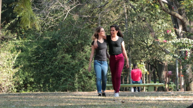 Zwei-Freundinnen-zusammen-zu-Fuß-in-den-Park,-umarmen-einander