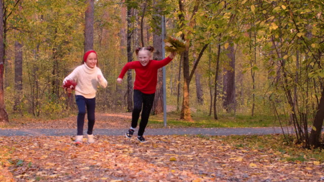 Happy-adorable-girls-running-with-leaf-bouquets-in-autumn-park-in-slow-motion