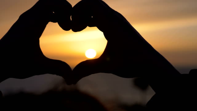Frau-die-Hände-machen-Herzform-bei-Sonnenuntergang.-Liebe,-Romantik,-Natur