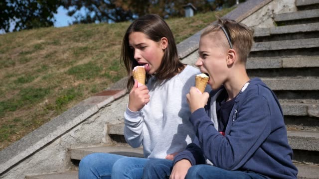 junges-attraktives-Paar-sitzt-auf-der-Treppe-lächelnd-und-Eis-essen