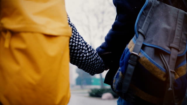 Camera-moves-around-happy-relaxed-young-romantic-tourist-couple-with-casual-backpacks-walking-together-on-a-winter-day.