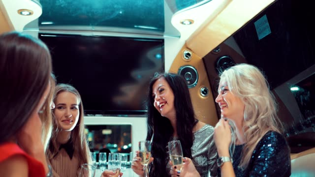 Girls-in-the-limo-are-celebrating.-Girls-clink-glasses-of-champagne-and-drink-it
