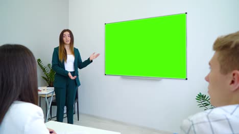 Junge-glücklich-Lehrerin-in-der-Nähe-mit-einem-green-Screen-Brett-unterrichten-von-Schülern-im-Klassenzimmer