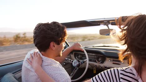 Young-white-couple-driving-open-top-car,-back-view,-close-up