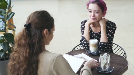 Frauen-skizzieren-und-sprechen-im-café
