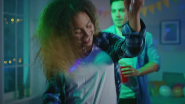 At-the-Wild-House-Party:-Beautiful-Black-Girl-Dances-in-Neon-Lights,-Holding-Red-Cup-with-Drink.-In-the-Background-Other-Teenagers-Having-Fun,-Clubbing.