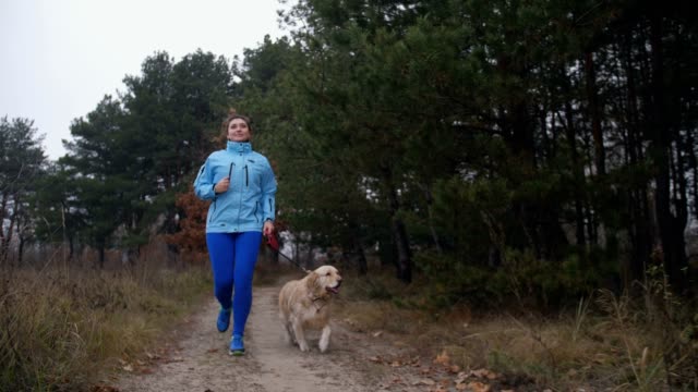 Sportlich-fit-Frau-mit-Hund-Joggen-im-herbstlichen-Wald