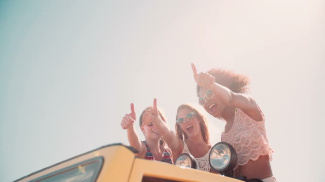 Afro-girl-and-friends-thumbs-up-on-road-trip