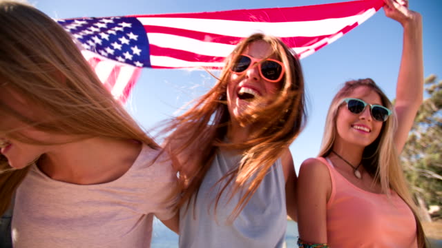 Enfriar-teen-amigos-sonriendo-y-sostiene-una-bandera-estadounidense