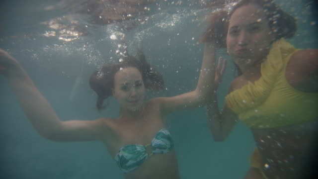 Girl-amigos-sonriendo-y-posando-en-bikinis-afortunadamente-underwater