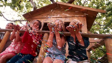 Children-blowing-colorful-paper-confetti-outdoors-in-tree-house