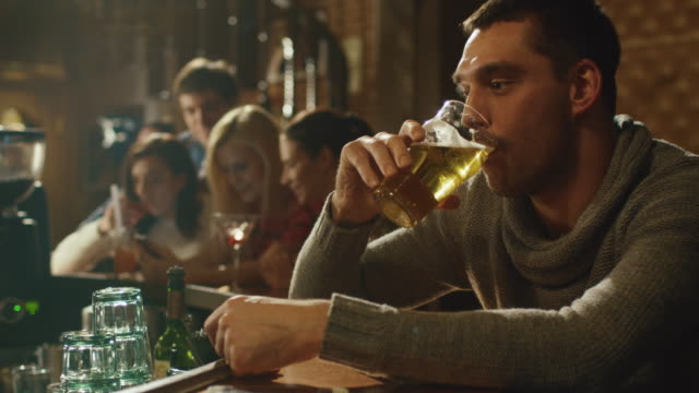 Attractive-man-is-drinking-lager-beer-in-a-crowded-pub.