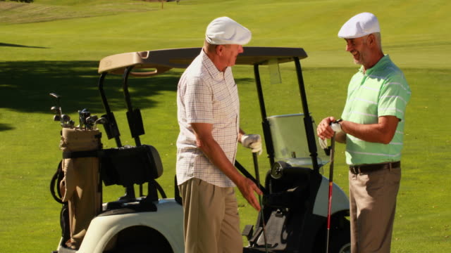 Dos-hombres-amigos-charlar-en-el-campo-de-golf-por-kart