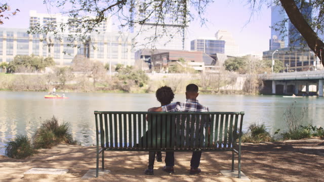 Afrikanische-amerikanische-paar-sitzen-zusammen-auf-einer-Bank-auf-die-Stadt-am-Wasser