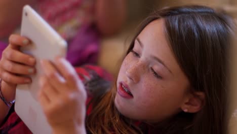 Primer-plano-de-una-joven-adolescente-usando-una-tableta-en-casa-con-su-amiga