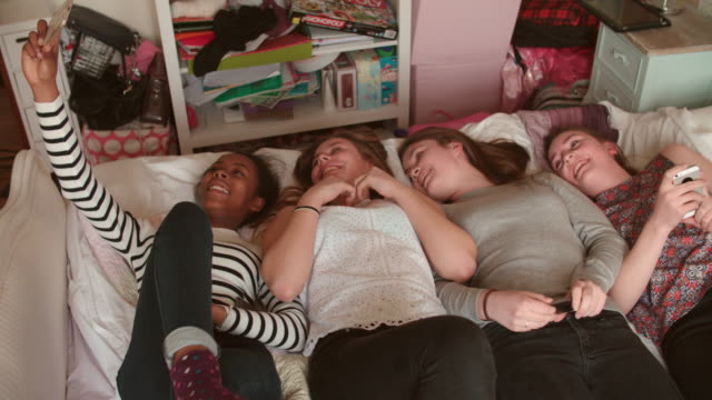 Mädchen-im-Teenageralter-auf-Bett-nehmen-Selfie-mit-Handy