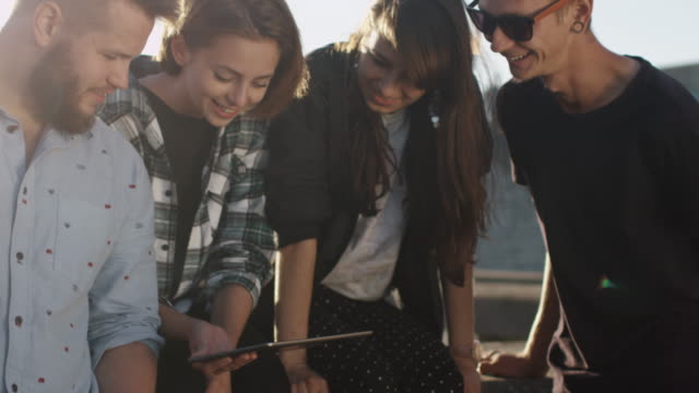 Grupo-de-adolescentes-con-Tablet-PC-para-el-entretenimiento-al-aire-libre-en-entorno-urbano