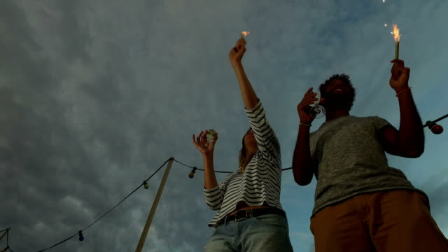 Low-angle-view-of-couple-dancing-with-firework-candles