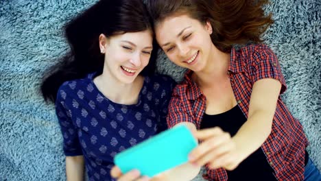 Top-Ansicht-von-zwei-hübschen-Mädchen-in-Pyjamas-machen-Selfie-Porträt-auf-dem-Bett-im-Schlafzimmer-zu-Hause