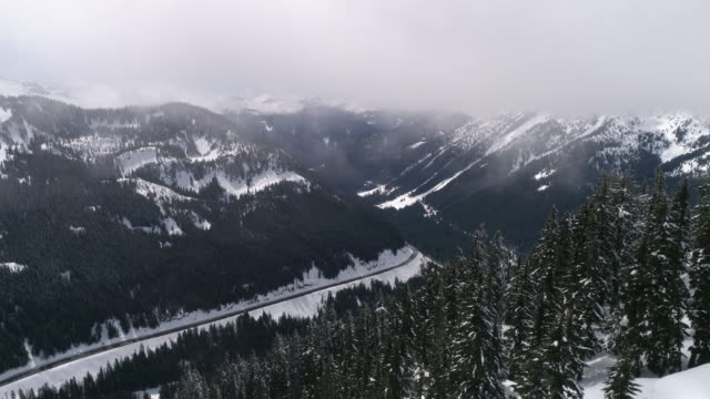 Winter-Roadtrip-Antenne-des-Reisenden-auf-Epic-Autobahn-im-verschneiten-Bergwald