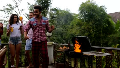 Junge-Leute-tanzen-kochen-Barbecue-Freundesgruppe-fröhliche-Zusammenkunft-Sommerterrasse-mit-Party