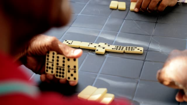 Activo-jubilado-a-hombre-Senior-jugando-dominó-con-los-amigos