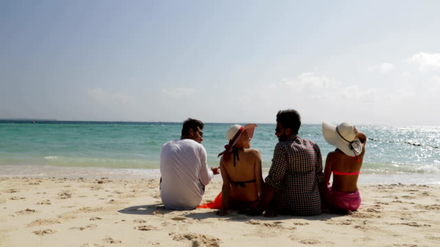Personas-sentadas-en-la-playa-hablando-atrás-posterior-vista,-hombres-y-mujeres-comunicación-turistas-grupo-en-vacaciones-de-verano