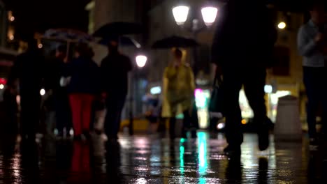 Zusammenfassung-Hintergrund-regnerischen-späten-Abend-in-der-Stadt-in-dunklen-Tönen-Naturale.-Regentropfen-fallen-auf-dem-bunten-Asphalt-von-Straßenlaternen-beleuchtet.-Unter-der-Menge-von-Fußgängern-gehen-Sie-zwei-Freunde-unter-Sonnenschirmen-und-sprechen.-Lebensstil-der-modernen-Stadt