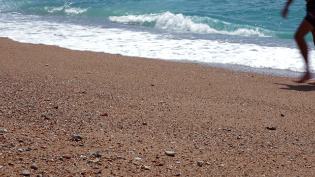 Fondo-de-vacaciones-de-verano-con-dos-jóvenes-caminando-por-la-playa-mientras-las-olas-del-mar-rompiendo-en-la-playa-de-arena-detrás-de-ellos
