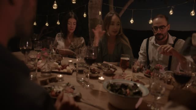 Young-friends-eating-at-elegant-countryside-rustic-dinner-party